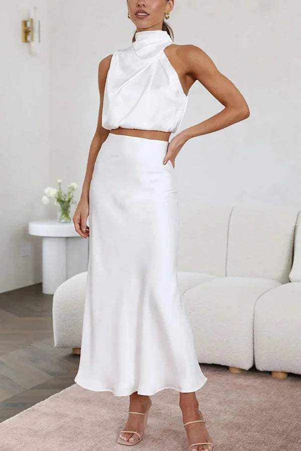 White satin halter top and skirt set for women by Zoha. Elegant and sleek duo features a flattering silhouette and a halter…
